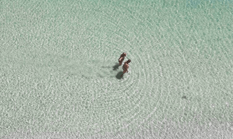 Due persone camminano nell'acqua cristallina.