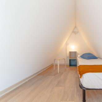 Stanza minimalista con letto singolo, atmosfera accogliente e rilassante.